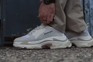 Close up side view of Balenciaga’s Triple S sneakers in white worn by a man on the street, tying the sneaker closer to the frame