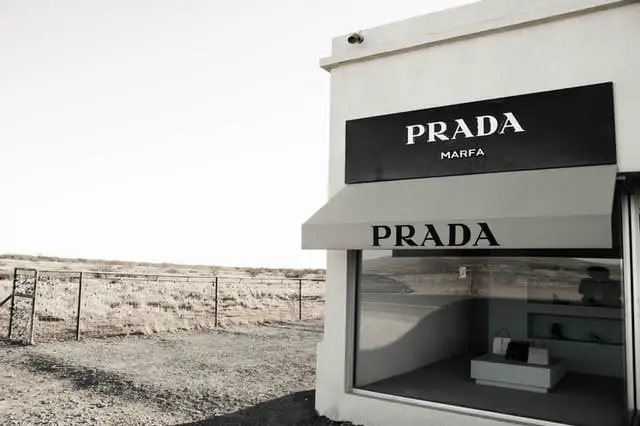 The window of a Prada shop in Marfa with simplistic black and white design with an empty landscape behind it.