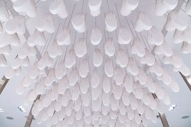 Hundreds of all-white sneakers hung from a white ceiling as a part of the fashion brand Kith’s ceiling sneaker art installation at Kith NYC.