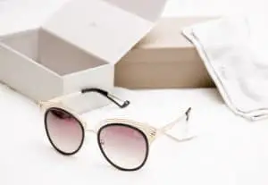 Rose-tinted Dior sunglasses with gold and black frame on white background