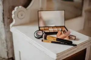 Makeup palates and brushes on white desk with mirror